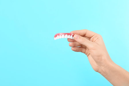 Woman holding teeth cover on color background. Space for textの写真素材