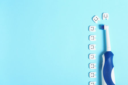 Flat lay composition with electric brush, small plastic teeth and space for text on color backgroundの写真素材