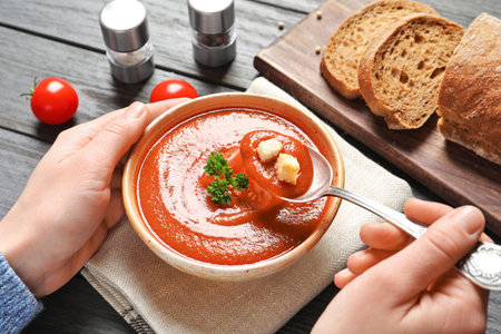 Woman eating fresh homemade tomato soup on wooden table, closeupの写真素材
