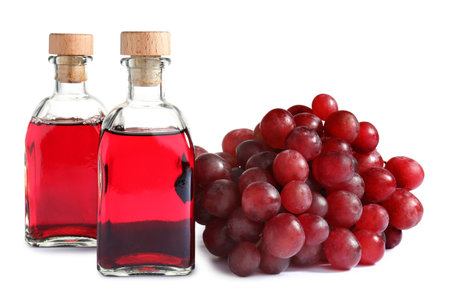 Bottles with wine vinegar and fresh grapes on white backgroundの写真素材