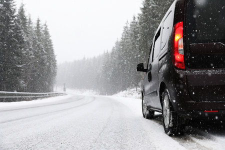 Country road with car on snowy winter day. Space for text
