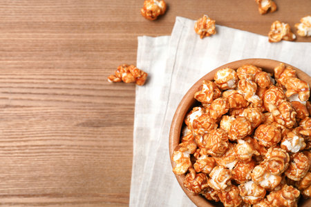 Bowl with caramel popcorn on wooden background, top view. Space for textの写真素材