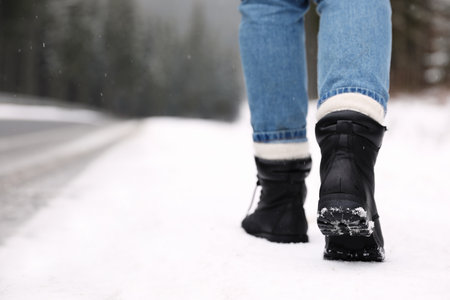 Woman walking outdoors on snowy winter day. Space for textの写真素材