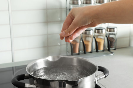 Woman salting boiling water in pot on stove, closeupの写真素材