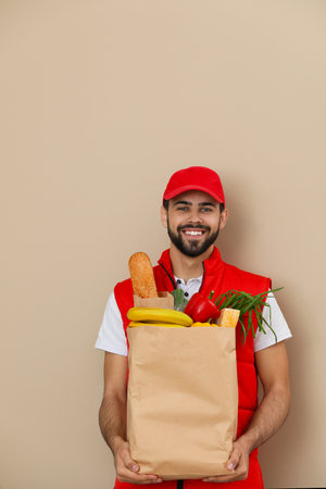 Man holding paper bag with fresh products on color background. food delivery serviceの写真素材
