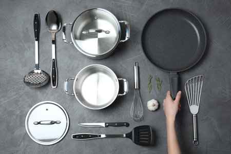 Woman holding frying pan over table with clean cookware, top viewの写真素材