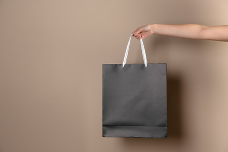 Woman holding paper shopping bag on color background. Mock up designの写真素材