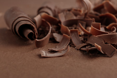 Curls of tasty chocolate on color background, closeupの写真素材