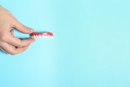 Woman holding teeth cover on color background, top view. Space for textの写真素材