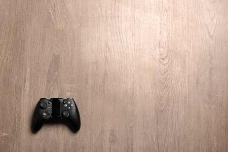 Video game controller on wooden background, top view with space for text