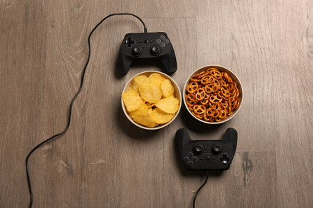 Flat lay composition with video game controllers and food on wooden background