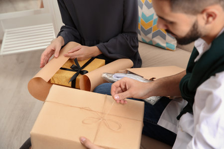 Young couple opening parcels in living room, closeupの写真素材