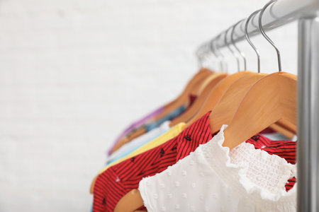 Wardrobe rack with stylish clothes on white background, closeup. Space for textの写真素材