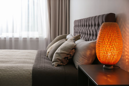 Large comfortable bed near light wall in modern room interiorの写真素材