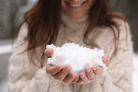 Young woman holding pile of snow in hands, closeupの写真素材