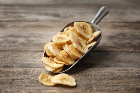 Scoop with banana slices on wooden background. Dried fruit as a healthy snackの写真素材