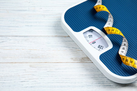 Scales, measuring tape and space for text on wooden background. weight lossの写真素材