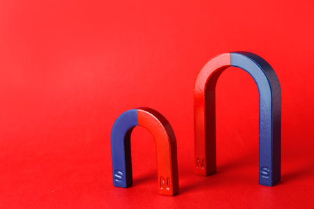 Red and blue horseshoe magnets on color background. Space for textの写真素材