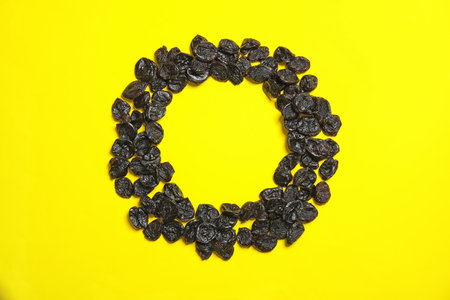 Frame made of tasty prunes on color background, top view with space for text. Dried fruit as a...