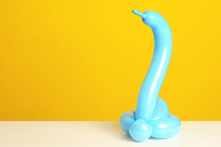 Snake figure made of modeling balloon on table against color background. Space for textの写真素材