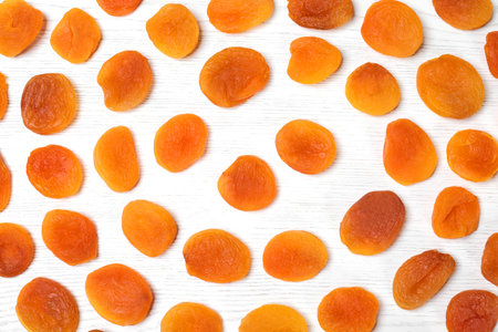 Flat lay composition with dried apricots on white wooden table. Healthy fruits