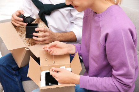 Young couple opening parcels in living room, closeupの写真素材