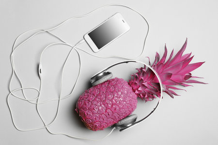 Pineapple with headphones and smartphone on gray background, top viewの写真素材