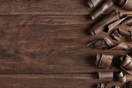 Yummy chocolate curls and space for text on wooden background, top viewの写真素材