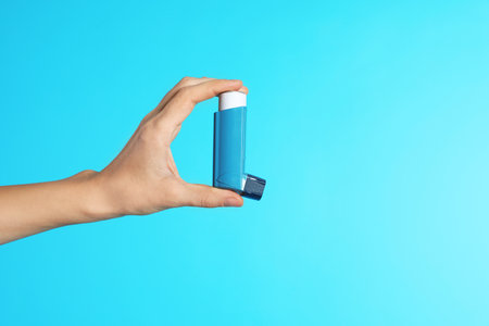 Female doctor holding asthma inhaler on color background, closeup view with space for text. medical objectの写真素材