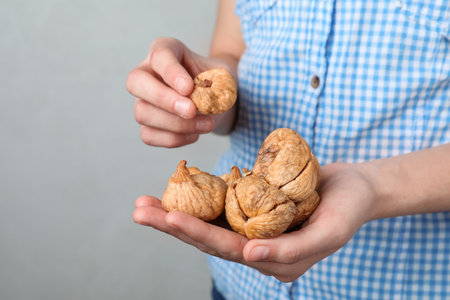 Woman holding handful of dried figs on light background, space for text. Healthy fruitsの写真素材
