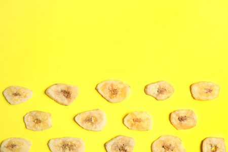 Flat lay composition with banana slices on color background, space for text. Dried fruit as a healthy snackの写真素材