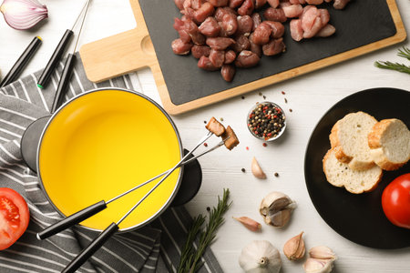 Flat lay composition with oil pot and meat fondue ingredients on wooden backgroundの写真素材