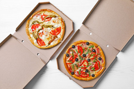 Cardboard boxes with tasty pizzas on wooden background, top viewの写真素材