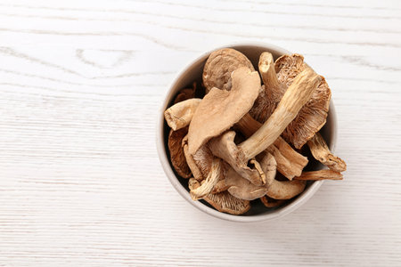 Bowl of dried mushrooms on wooden background, top view with space for textの写真素材