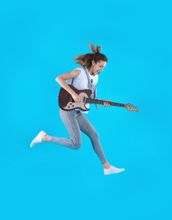 Young woman playing electric guitar on color backgroundの写真素材