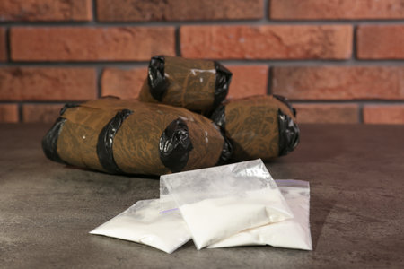 Hemp and cocaine in packages on gray table. drug addiction