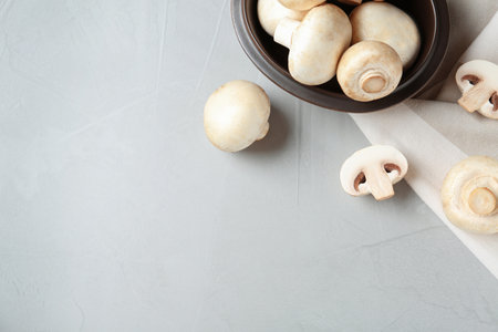 Fresh champignon mushrooms and plate on table, top view. Space for text