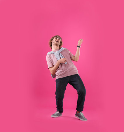 Young man playing air guitar on color backgroundの写真素材