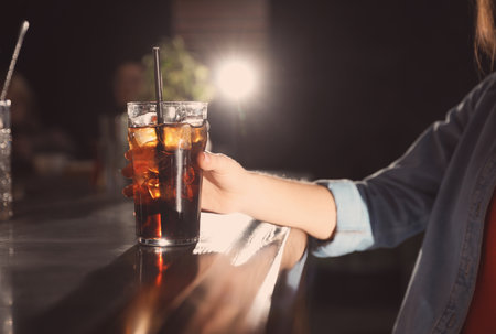 Woman with glass of refreshing cola at bar counter, closeupの写真素材