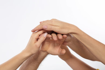 Young people holding hands together on white background, closeup. Team victory conceptの写真素材