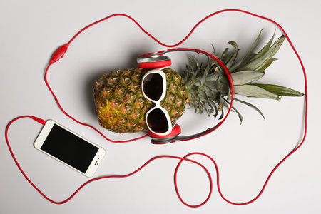 Pineapple with headphones and smartphone on gray background, top viewの写真素材