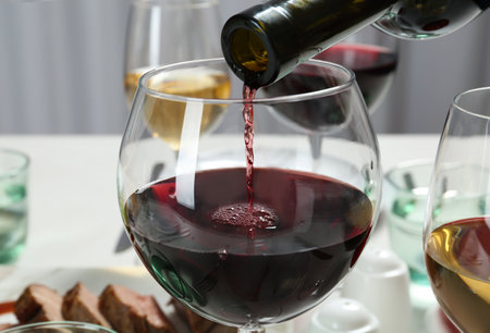 Pouring red wine into glass on table, closeupの写真素材
