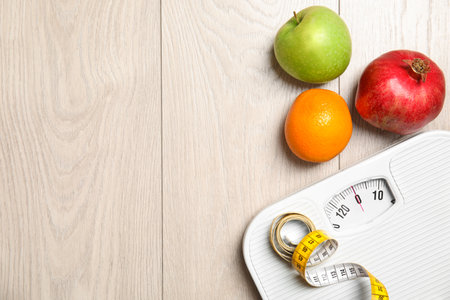 Flat lay composition with scales, measuring tape, fruits and space for text on wooden background. weight lossの写真素材