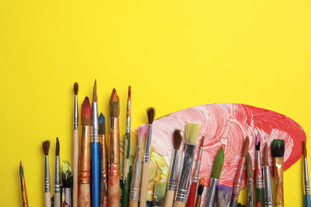 Different paint brushes and palette on color background, top view with space for textの写真素材