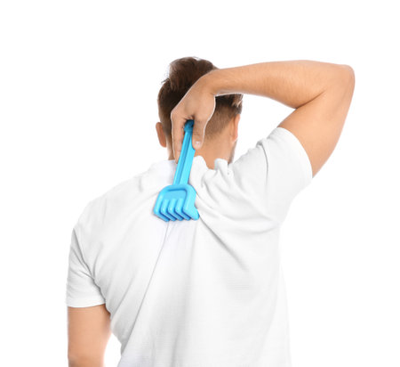 Young man scratching back with toy rake on white background. Annoying itchの写真素材