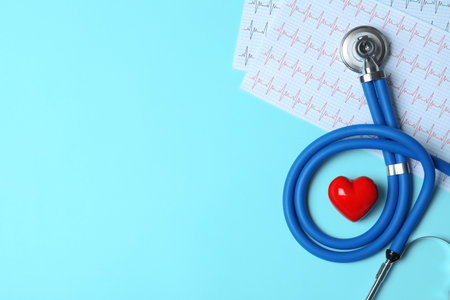 Stethoscope with red heart and cardiogram on blue background, flat lay. Space for textの写真素材