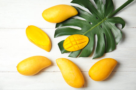 Flat lay composition with mango and tropical leaf on wooden backgroundの写真素材