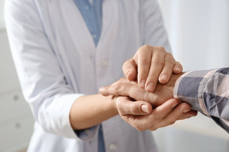Female doctor comforting man on light background, closeup of hands. Help and support conceptの写真素材