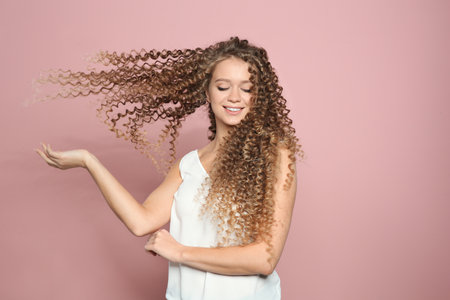 Portrait of beautiful young woman with shiny wavy hair on color backgroundの写真素材