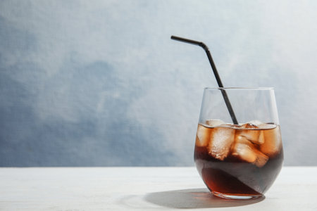 Glass of refreshing cola with ice cubes and straw on table. Space for textの写真素材